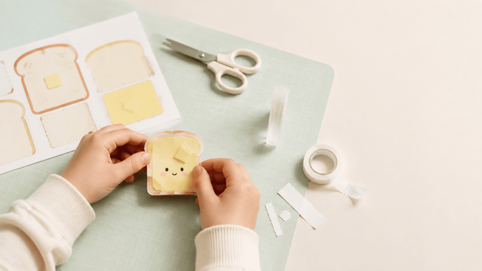 Hands assembling a handmade butter paper squishy with scissors, tape, and glue